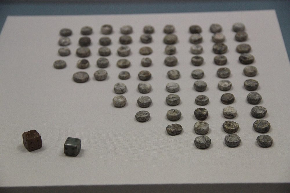 Antique game pieces and dice laid out on a board